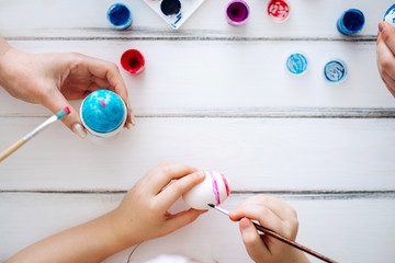 Close up female hands blue Easter eggs White background. Flat lay Home tradition of painting eggs