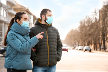 Couple wearing disposable masks outdoors. Dangerous virus