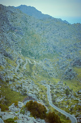 Mountain road in Tramuntana range. The mountain is rocky and full of bushes. In the background there is the Mediterranean Sea. Mallorca, Spain