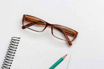 notebook, pencil and glasses on white background isolated