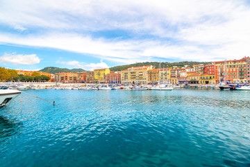 Boats in the marina and cafes and shops along the sea at the colorful old port of the Mediterranean city of Nice, France, along the French Riviera.