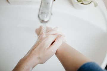 Closeup of a woman washing her hands in bathroom to prevent Covid-19 viral infection. Recommended...