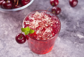 Glass with fresh homemade cherry sweet iced tea or cocktail, lemonade with mint. Refreshing cold drink. Summer party.