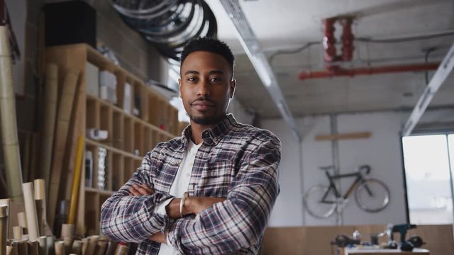 Portrait of young male business owner in workshop for building sustainable handmade bamboo bicycles - shot in slow motion  