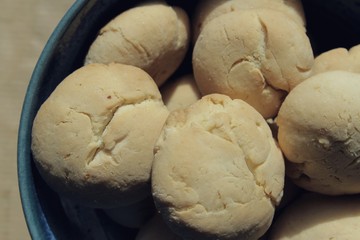 Artisan biscuits: homemade sugar dessert with fragrant lemon zest and citrus juice, delicious cookies for tea time at home, stored in beautiful handmade blue pottery bowl on the kitchen table.