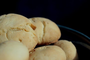 Artisan biscuits: homemade sugar dessert with fragrant lemon zest and citrus juice, delicious cookies for tea time at home, stored in beautiful handmade blue pottery bowl on the kitchen table.