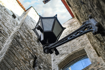 Fototapeta na wymiar Selective focus shot of a 19th century street lamp seen from below in a narrow medieval alley in the town of Tallinn Estonia.