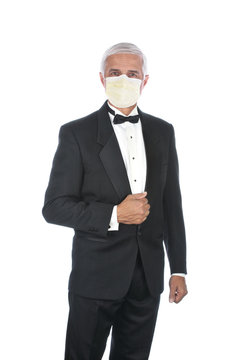 Mature Adult Male Wearing Tuxedo and Covid-19 protective mask, holding lapel and one hand at side, isolated on white.