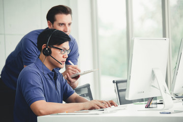 Young handsome male customer support phone operator with headset working in call center.