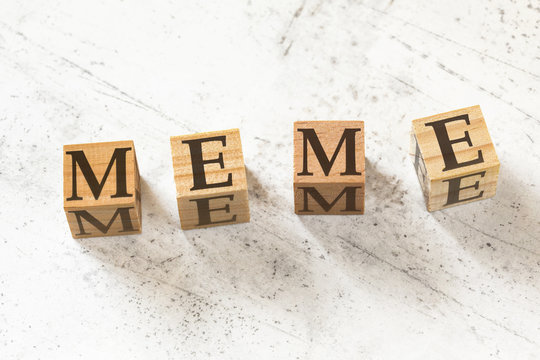 Four Wooden Cubes With Word MEME On White Working Board.