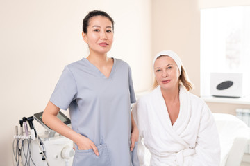 Fototapeta premium Attractive mature woman in bathrobe regularly visiting her cosmetologist in beauty salon