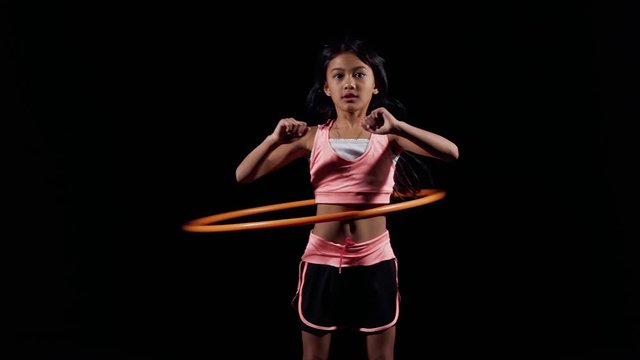 A little asian girl practices hula-hoop on slow motion