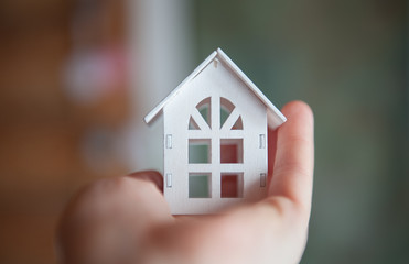 Toy wooden house whiteToy wooden house of white color is in the hand close-up. The concept of stay at home. Quarantine, epidemic  close-up. The concept of stay at home. Quarantine, epidemic