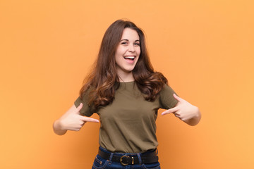 young pretty woman looking proud, arrogant, happy, surprised and satisfied, pointing to self,...