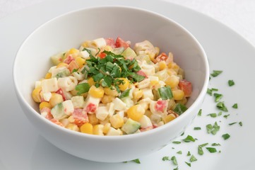 a bowl of crab sticks salad with sweet corn, cucumber, bell pepper, and egg dressed with mayonnaise