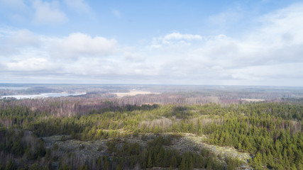 Spring landscape aerial view. Green forest and rocks. Blue cloudy sky. Finland