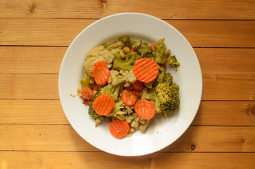 Vegetarian mix of vegetables.A plate with carrots and broccoli on wooden background.