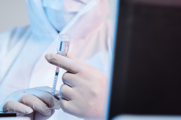 The microbiolog gets the vaccine into the syringe. Glass bottle in a doctor's hand. A bottle with a...