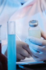 Fototapeta premium Glass medical bottle in a doctor's hand. A bottle with a medicine holds a hand in silicone gloves in a hospital. The nurse prepares the vaccine. A breakthrough in treatment. Antiviral vaccination.