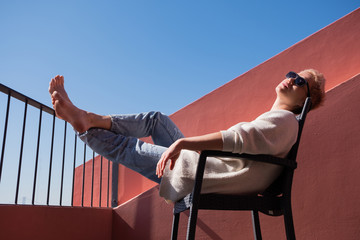 A charming woman rests on her balcony lying on a chair during a quarantine in Europe