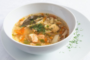 a bowl of cod and salmon soup decorated with dill