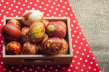 Chicken eggs colored with old-fashioned natural method by onion husks. Brown eggs with different natural patterns in box on red. Selective focus with copyspace. Traditional Easter and Spring concept