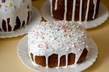 Traditional delicious celebration Easter bread with white glaze and colourful candy powder on a plate. Concept of handcrafted annual orthodox holidays breakfast. Russian, Ukrainian Traditional Kulich
