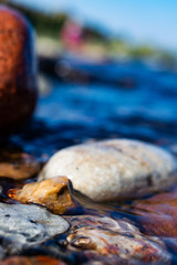 sea stones lying on the seashore, ocean in sunny weather washed by sea or ocean water