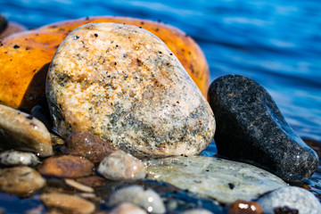 sea stones lying on the seashore, ocean in sunny weather washed by sea or ocean water