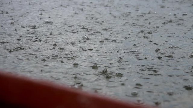 Expanse of river along which drops of heavy rain are beating, torrential rain caught tourists in boat aback, stopped in middle of river, waiting for rain, shooting from boat, bubbles on water