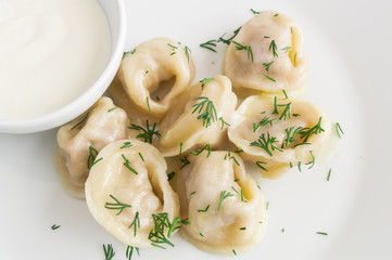 a portion of dumplings in butter sprinkled with dill served with sour cream