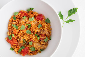 a bowl of bulgur plov with meat decorated with parsley