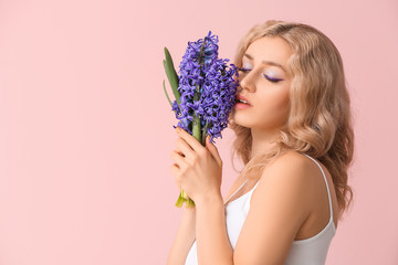 Beautiful young woman with hyacinth flowers on color background