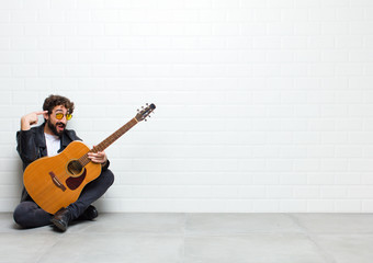 young cool musician man, playing rock and roll music sitting on the floor