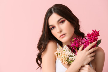 Fototapeta premium Beautiful young woman with hyacinth flowers on color background