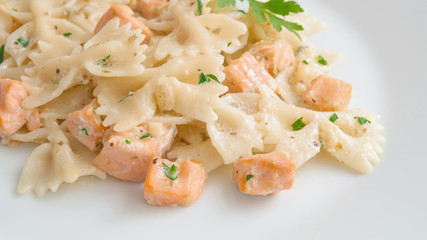 fried salmon chops and farfalle pasta with cream sauce decorated with parsley