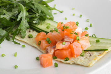 salmon chops on cucumber and thin 
omelette sprinkled with onion served with arugula leaves 