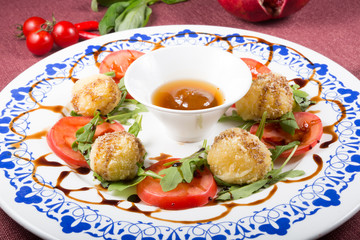 Fried cheese balls with tomatoes and green arugula