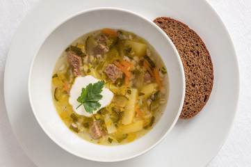 vegetable soup with meat served with bread and sour cream