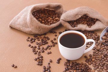 Cup of hot coffee and beans on table