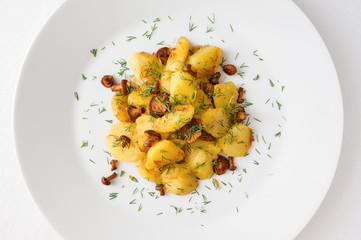 a plate with potato fried with chanterelles and onion, sprinkled with dill