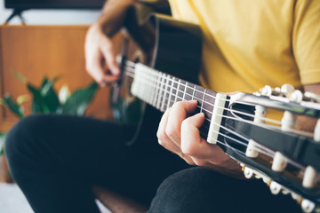 Close-up of a man hands holding and playing Acoustic Guitar at home with beautiful modern interior....