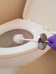 Closeup of lady using brush to wash toilet.  Hygiene concept.