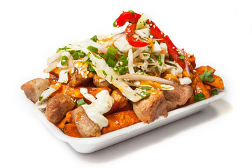 Peruvian street food:  Asian version of the salchipapas with pork rind and sweet potato fries  with chili peppers, decorated with veggies and sesam seeds on the top and served on a white plate