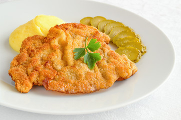 thin breaded schnitzel with mashed potato and pickled cucumber