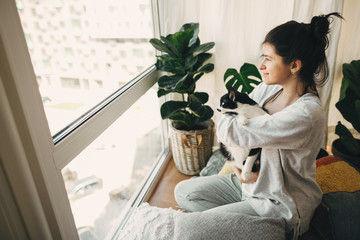 Stay home stay safe. Hipster girl hugging cute cat, sitting together at home during coronavirus...