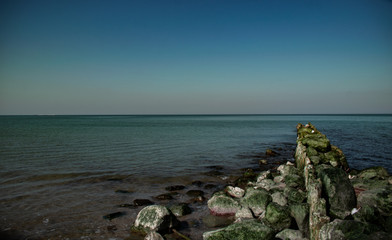 view of the rocky beach of the sea or ocean in sunny weather with clear blue sky