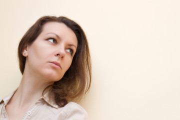 Fototapeta premium Brunette offended without strong makeup on a beige background
