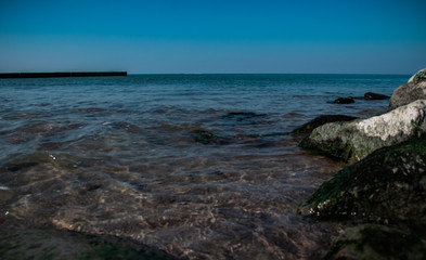 view of the rocky beach of the sea or ocean in sunny weather with clear blue sky