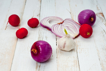 Red onion, radish and head of garlic. Background for cooking. Vegetables. Healthy nutrition, vitamins and vegetarianism.